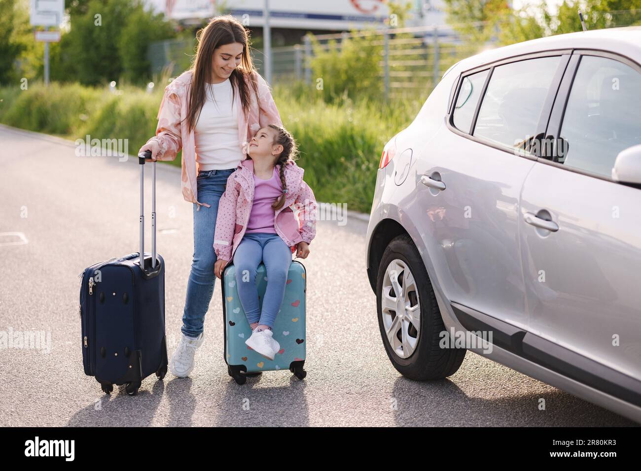 Famiglia in piedi in auto con valigie e viaggio in attesa. Bambina seduta  su valigia per bambini Foto stock - Alamy
