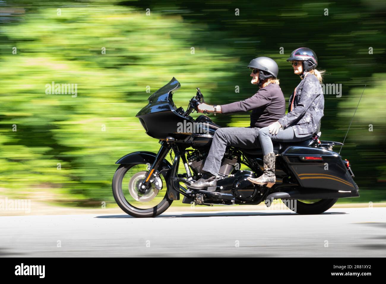 foto panoramica di una moto nera con due piloti che mostrano il movimento mentre percorrono le strade delle montagne Foto Stock