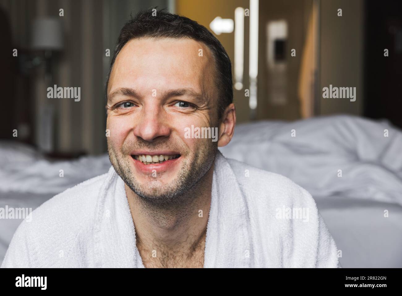 Ritratto di un giovane uomo europeo sorridente in accappatoio di cotone bianco Foto Stock