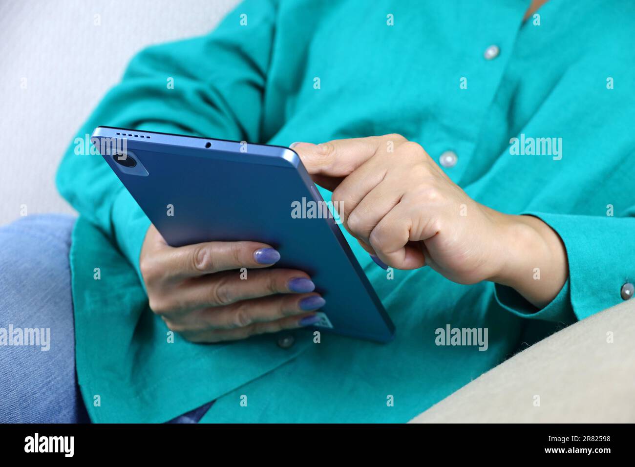 Donna sdraiata con un tablet PC sul divano. Concetto di guardare video, tempo libero a casa Foto Stock