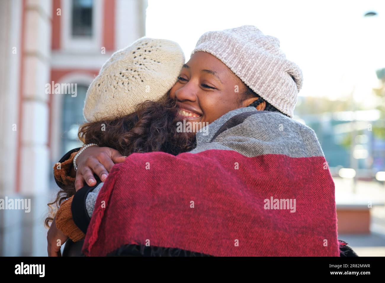 Due donne multirazziali felici amici abbracciarsi e sorridere sulla strada della città. Foto Stock