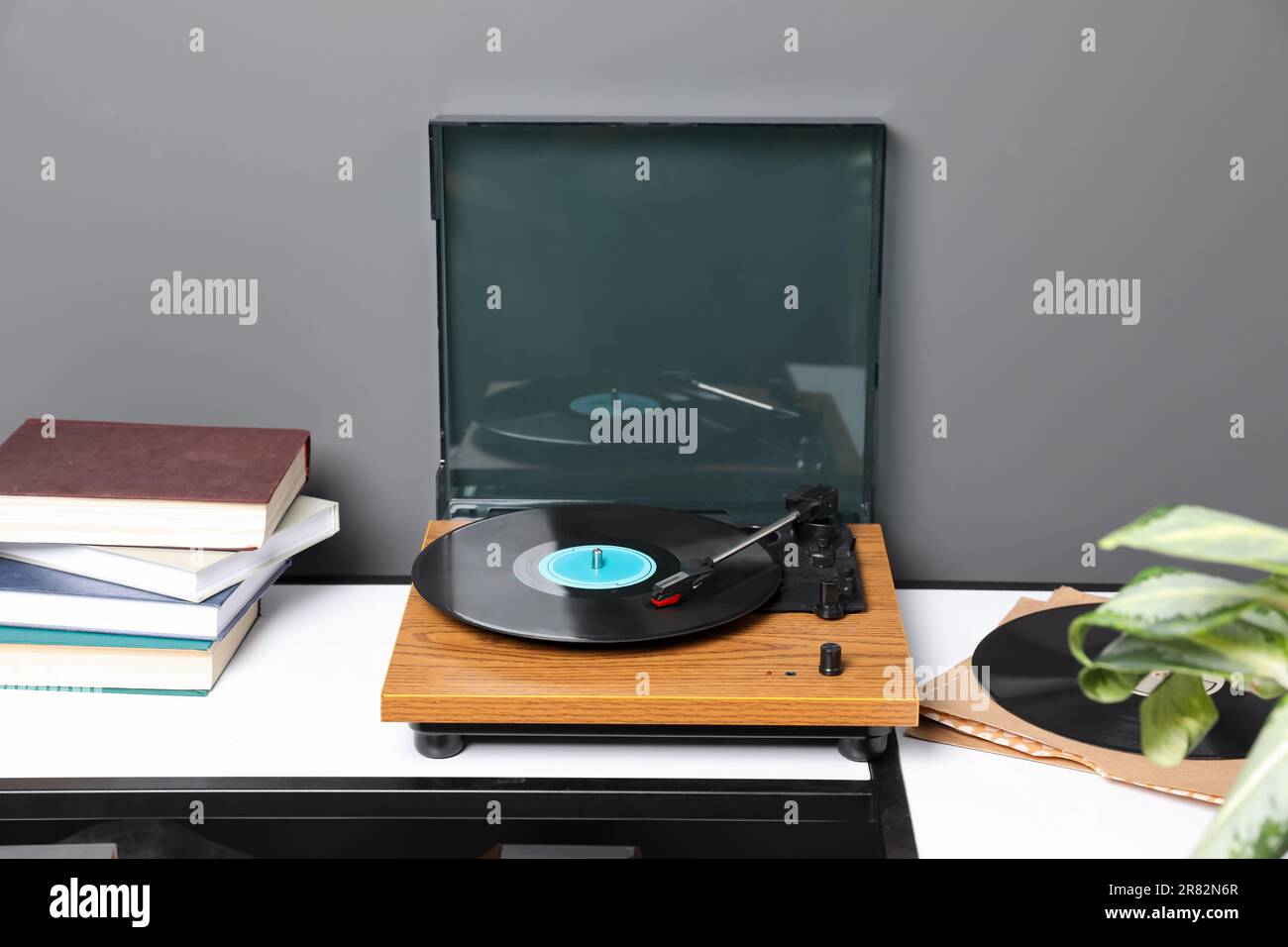 Elegante giradischi con disco in vinile vicino alla parete grigia in camera Foto Stock