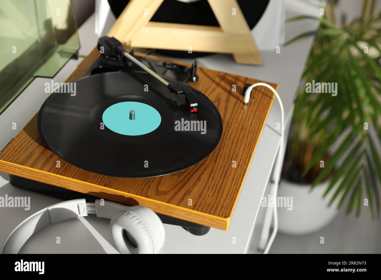 Elegante giradischi con disco in vinile e cuffie su cassettiera bianca a casa Foto Stock
