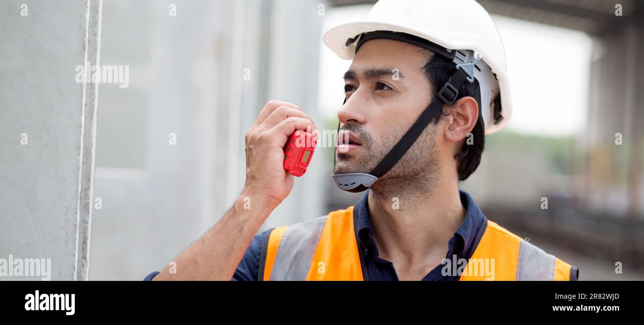 Un giovane ingegnere che utilizza il comando radio con un lavoratore in cantiere, architetto o appaltatore parla con la radio per il controllo e la pianificazione dello sviluppo Foto Stock