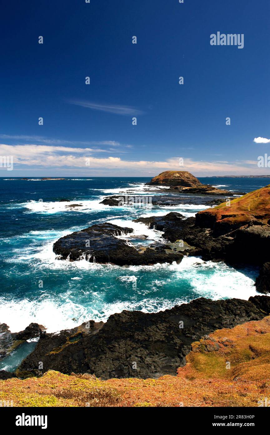 La costa meridionale di Phillip Island a Victoria, Australia, si affaccia sui mari scoscesi dello stretto di Bass e sulle sue coste rocciose si infrangono le onde. Foto Stock