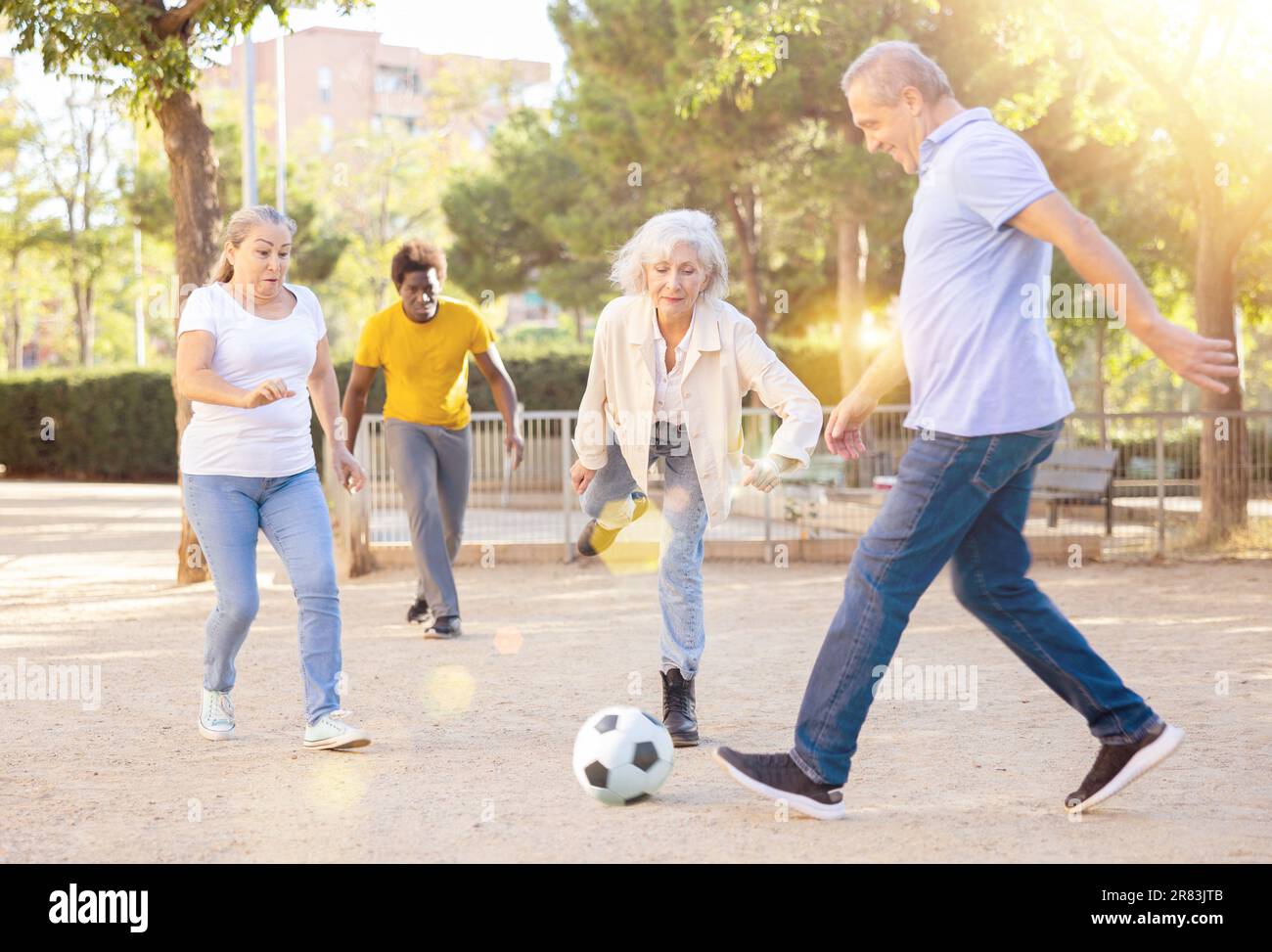 Maschi e femmine allegri che calci la palla nel parco Foto Stock