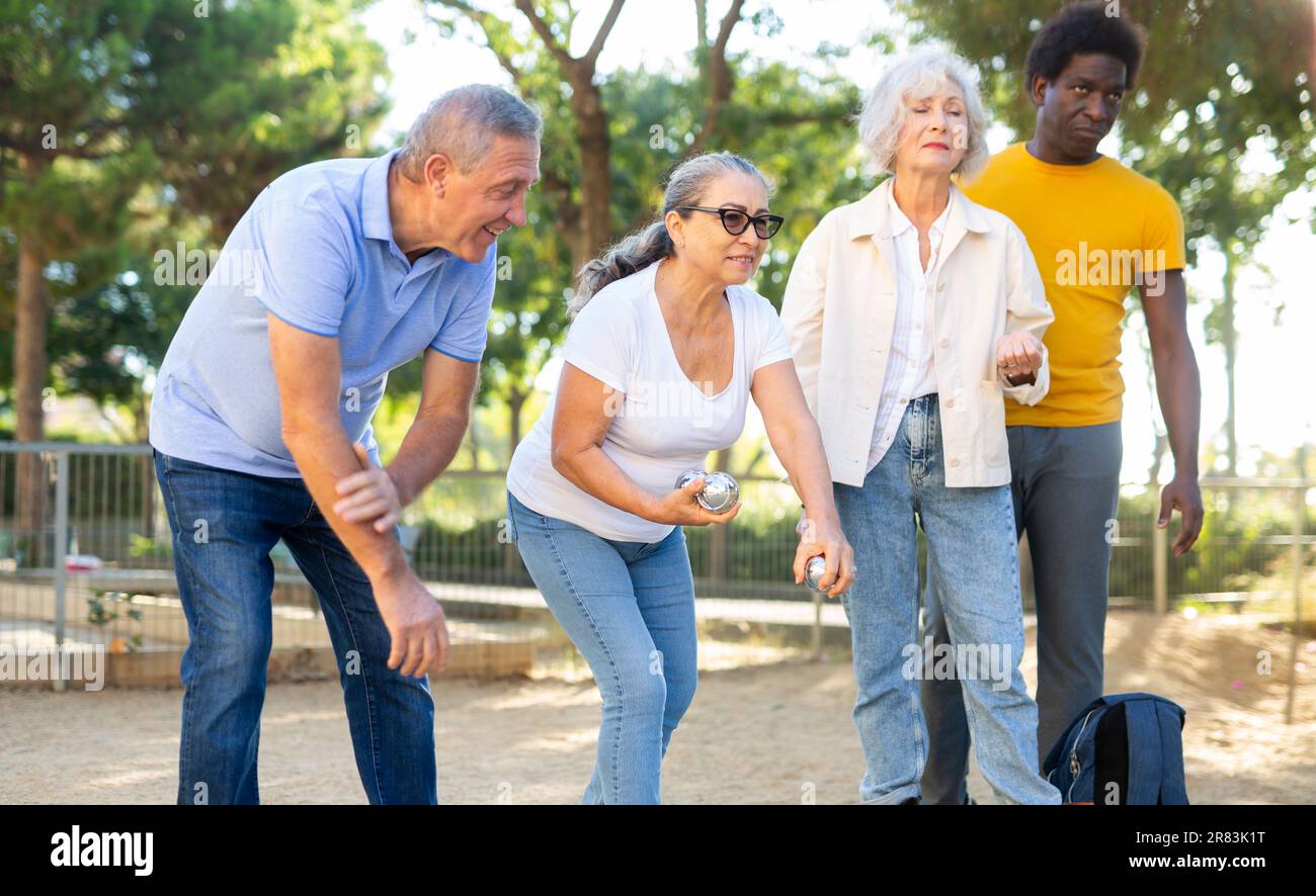 Un gruppo di adulti maturi che giocano a un gioco di patanque all'aperto in un parco Foto Stock