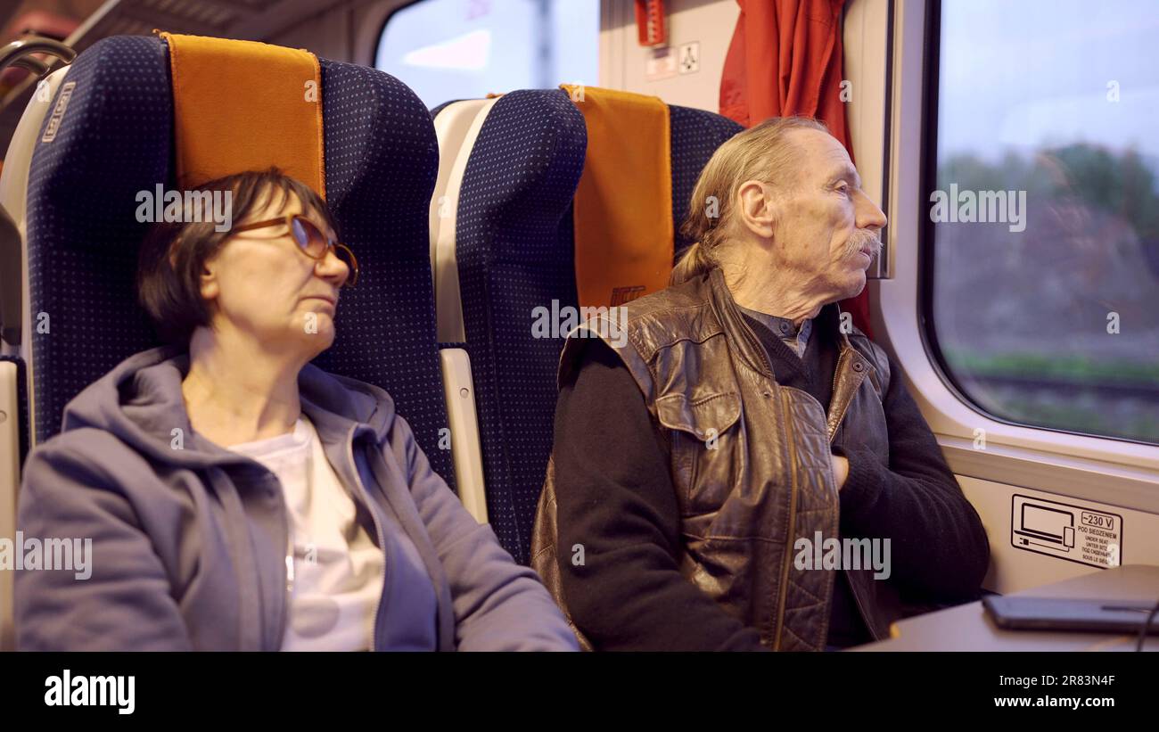 Una coppia anziana viaggia in treno, un anziano guarda fuori dalla finestra, una donna che dorme Foto Stock