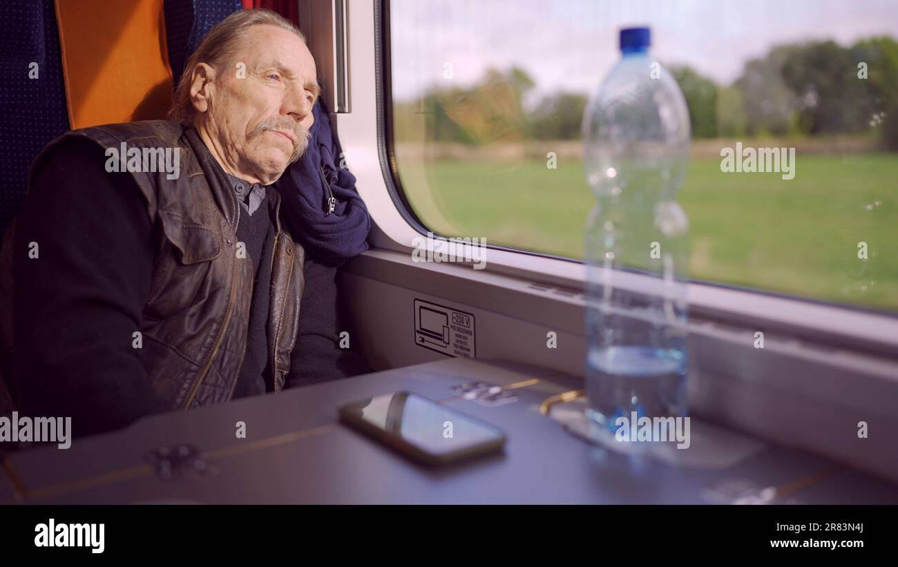 Primo piano di anziani con gli occhiali viaggia in un treno e guarda fuori dalla finestra Foto Stock