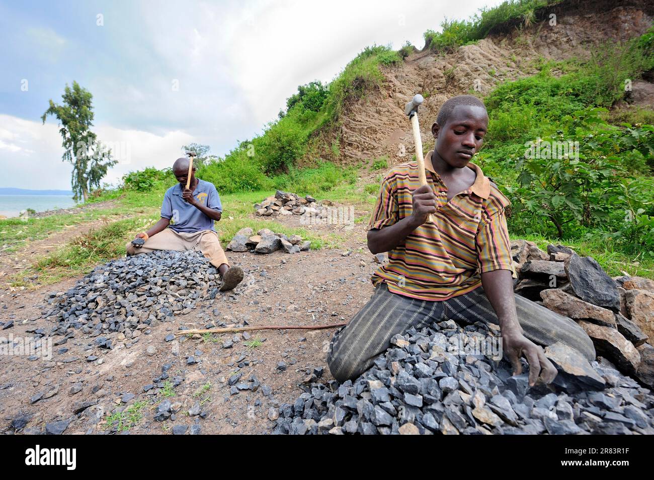 Gli uomini sfondano la pietra come superficie stradale, vicino a Bukavu, Kivu meridionale, Repubblica Democratica del Congo Foto Stock