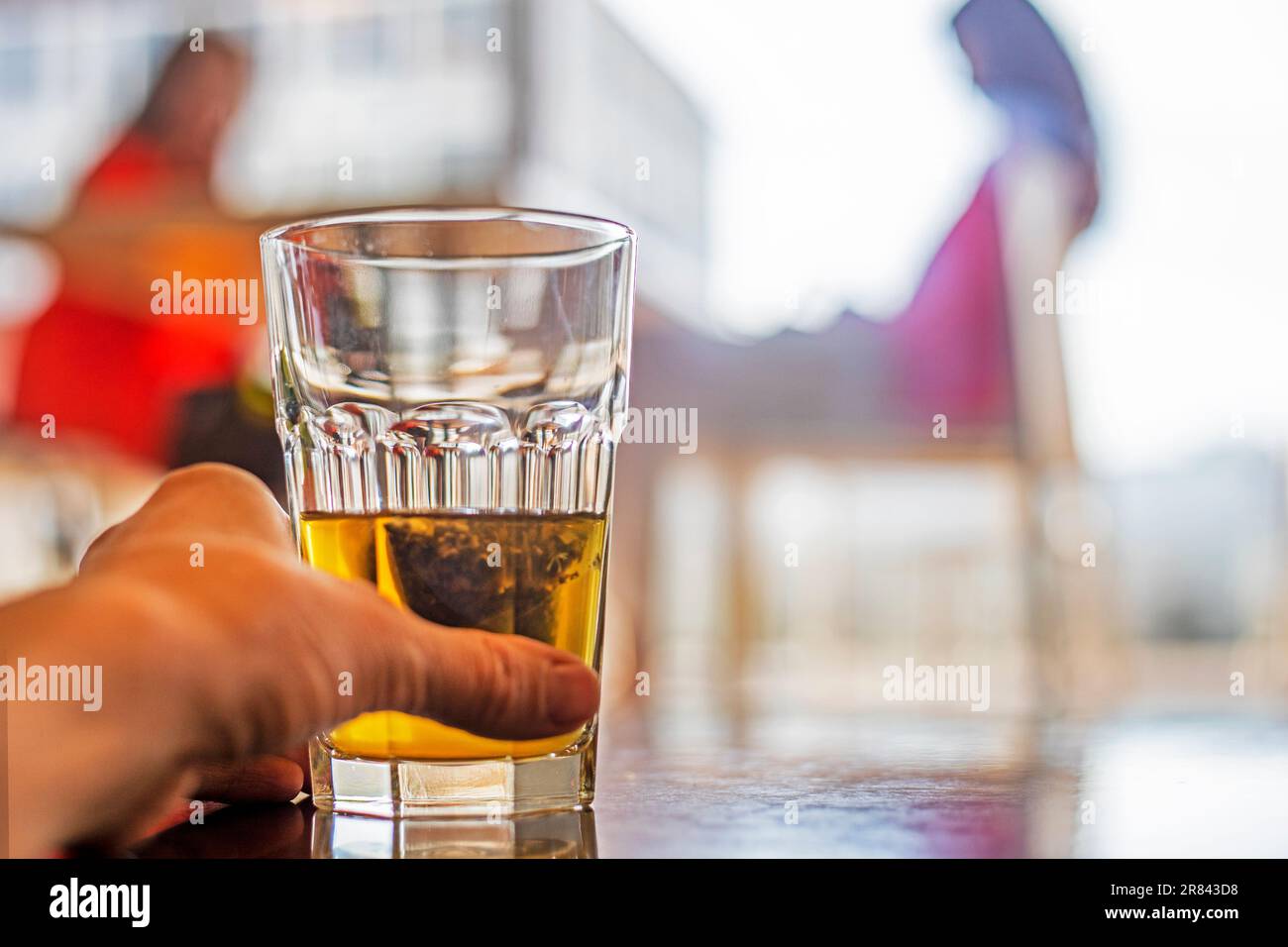 tenere una tazza di vetro con tè verde in una borsa in un caffè. Snack Foto Stock