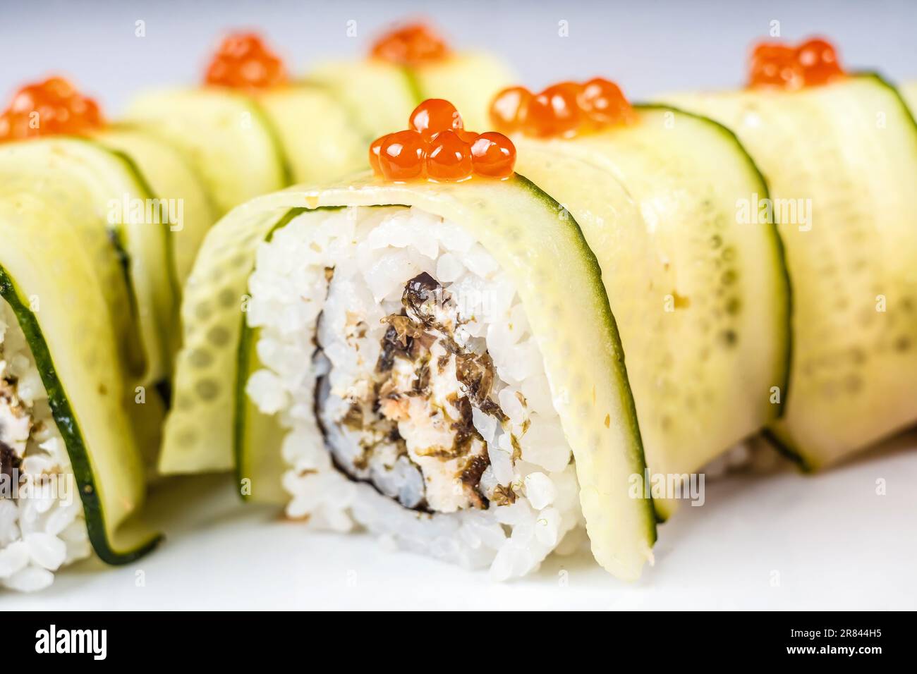 Un colorato rotolo californiano, pieno di prodotti freschi e frutti di mare come cetriolo e caviale rosso per un piatto di sushi sano ma delizioso. Foto Stock