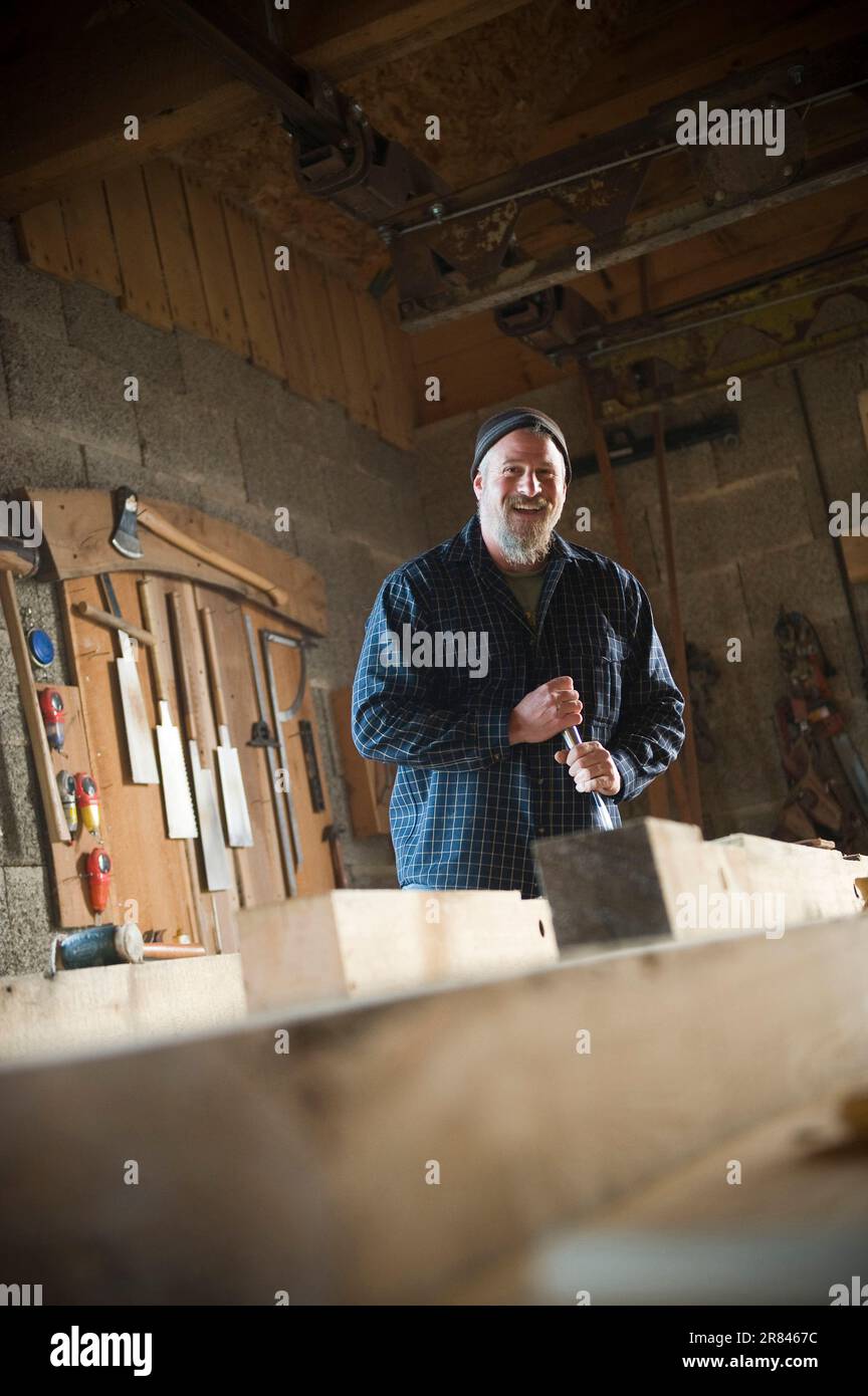 Prendendo una rottura, un framer del legno ride mentre pulisce fuori un giunto mortasa con uno scalpello mortasa. Foto Stock