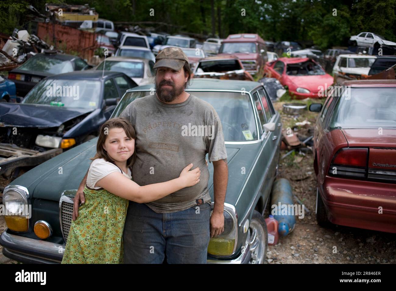 Un uomo abbraccia sua figlia nel junkyard in NC. Foto Stock