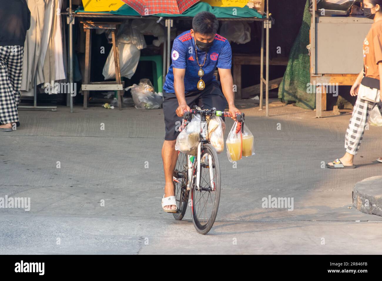 SAMUT PRAKAN, THAILANDIA, MAR 03 2023, Un ciclista cavalca una bicicletta e porta lo shopping in borse Foto Stock