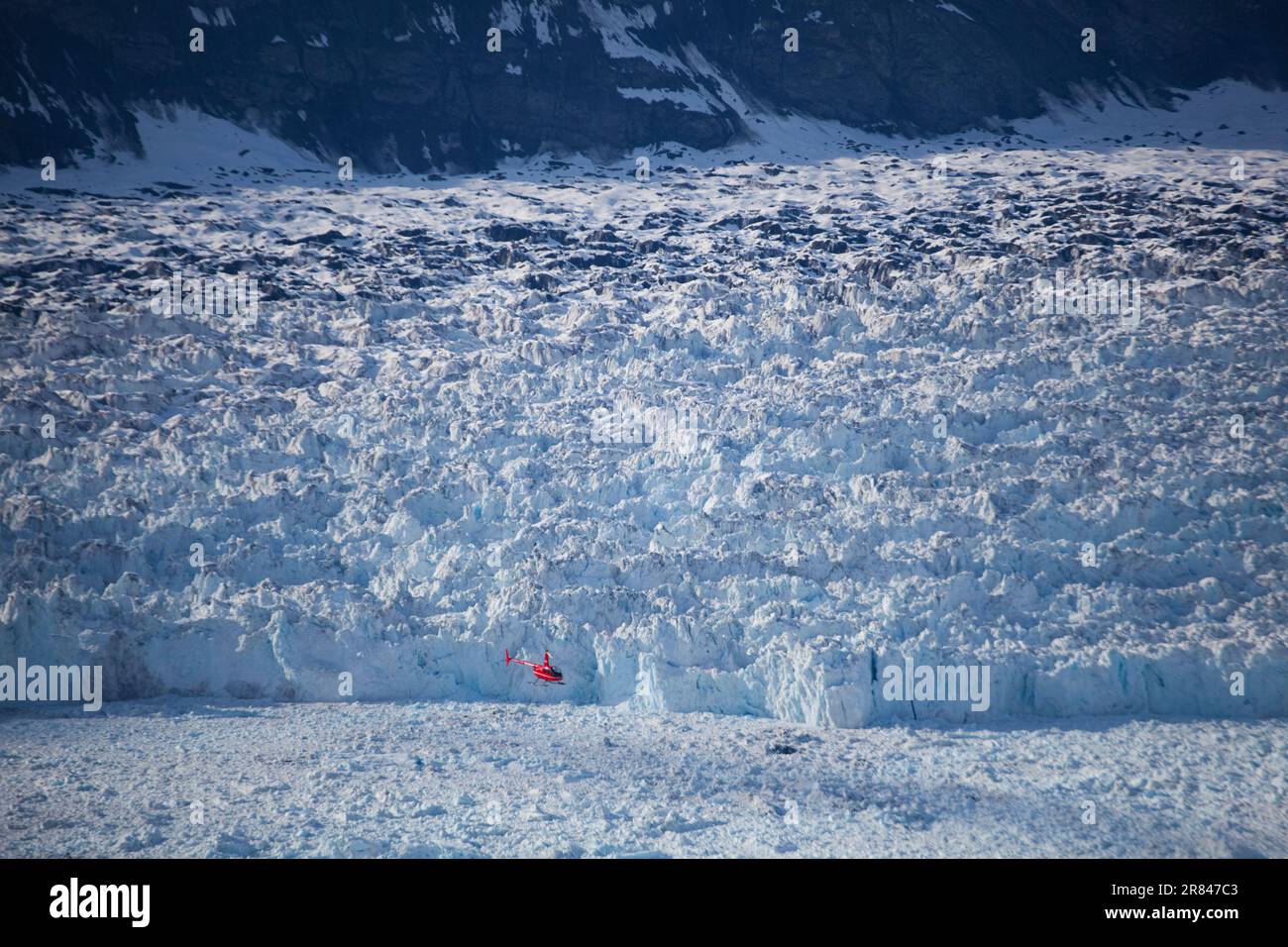 Un elicottero vola quasi al livello del mare, vicino alla faccia calvante del ghiacciaio Columbia, vicino a Valdez, Alaska. Foto Stock