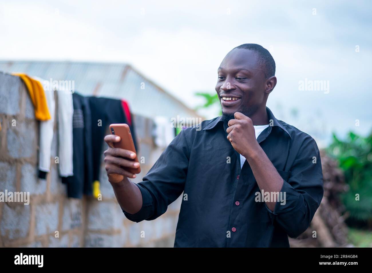 eccitato nero uomo utilizzando il suo telefono cellulare. utilizzo della tecnologia wireless Foto Stock