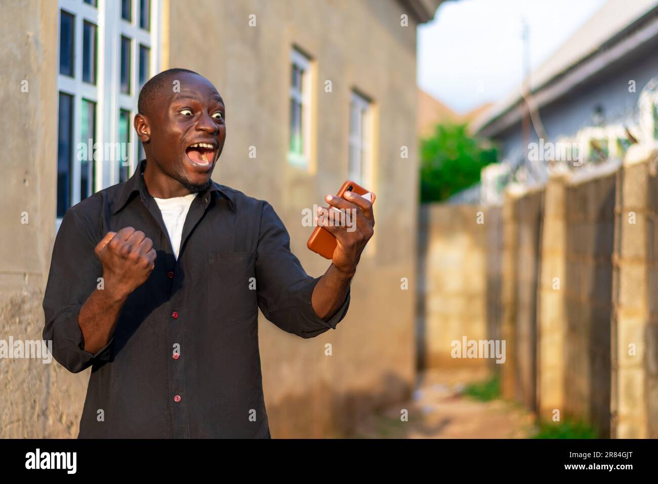nero africano uomo molto felice ed eccitato per il successo che ha visto sul suo telefono cellulare Foto Stock