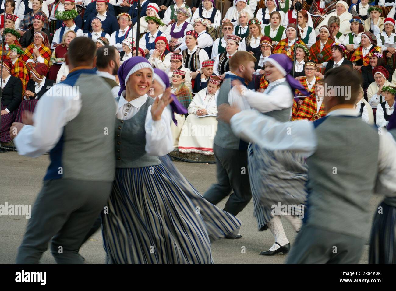 Dobele, Lettonia - 27 maggio 2023. La gente in costume nazionale guarda un'esibizione di un gruppo di danza folcloristica in movimento al XXVII Nationwide Latvian Song and Foto Stock