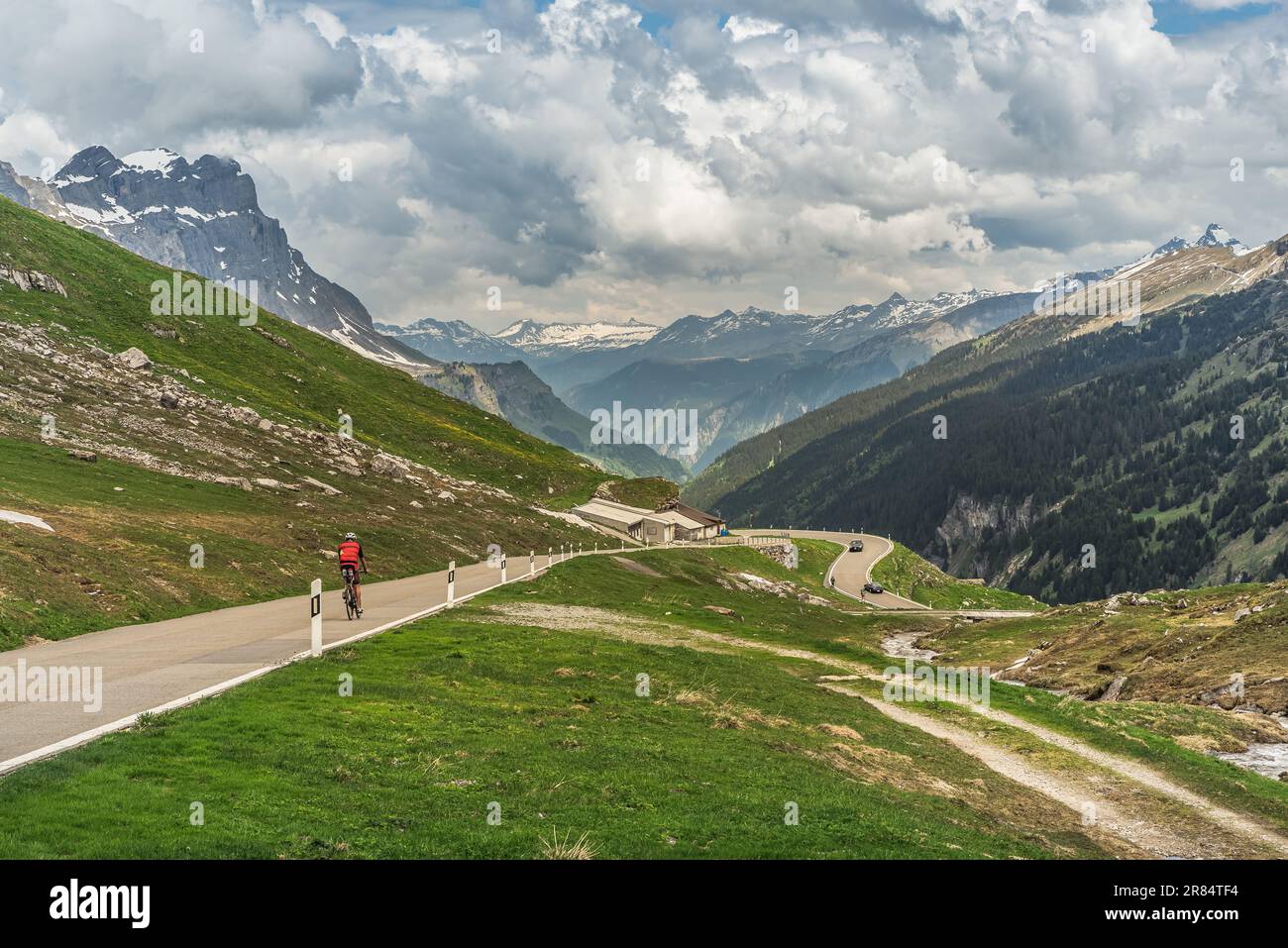 Ciclista sulla strada del passo di Klausen, panorama montano nelle Alpi svizzere, Spiringen, Canton Uri, Svizzera Foto Stock