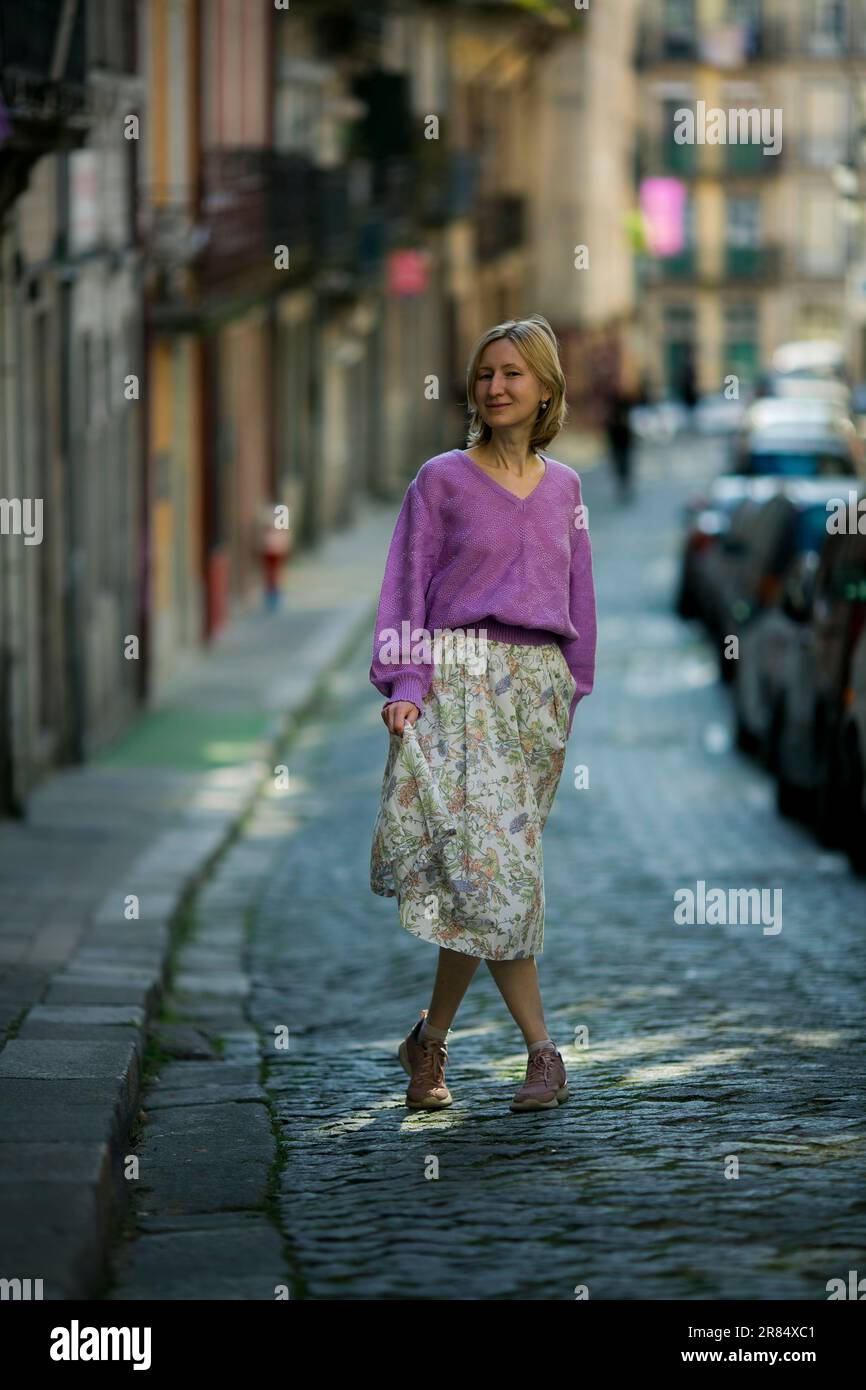 Donna in gonna che cammina per le strade del centro di Porto, Portogallo. Foto Stock