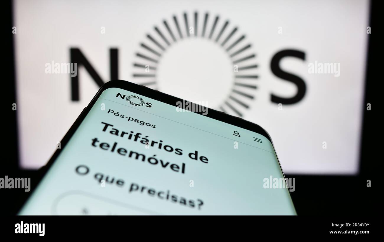 Smartphone con pagina Web della società di telecomunicazioni NOS SGPS SA sullo schermo davanti al logo aziendale. Messa a fuoco in alto a sinistra del display del telefono. Foto Stock