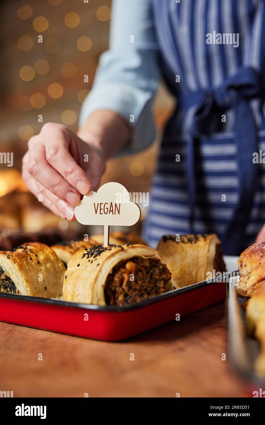 Sales Assistant in Bakery mettere Vegan Label in Savoury Roll appena sfornato Foto Stock