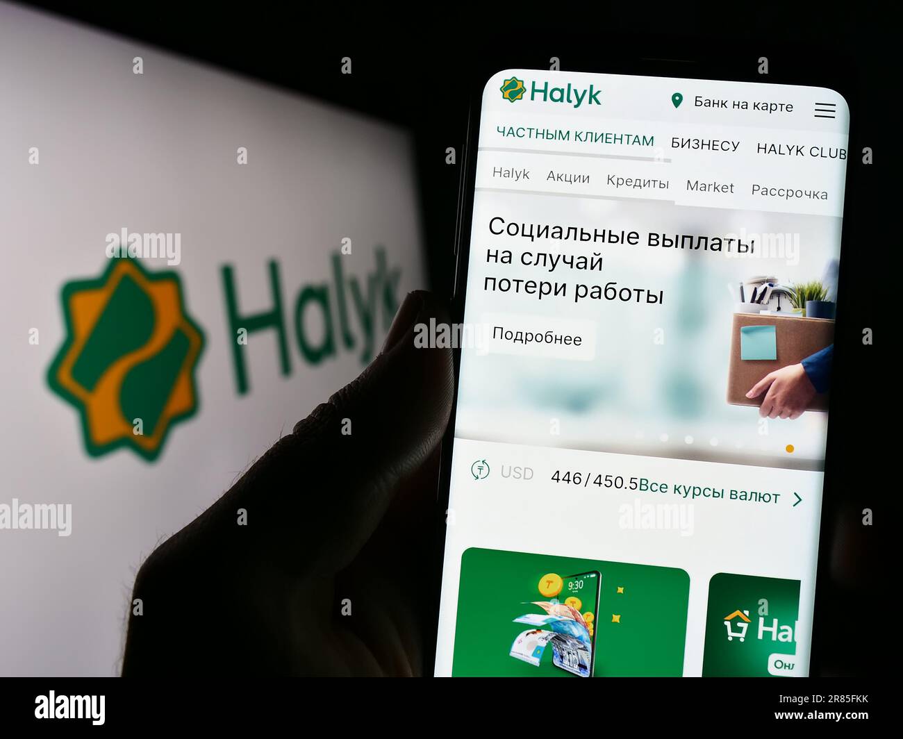 Persona che tiene il cellulare con il sito web della società di servizi finanziari kazaka Halyk Bank sullo schermo di fronte al logo. Messa a fuoco al centro del display del telefono. Foto Stock