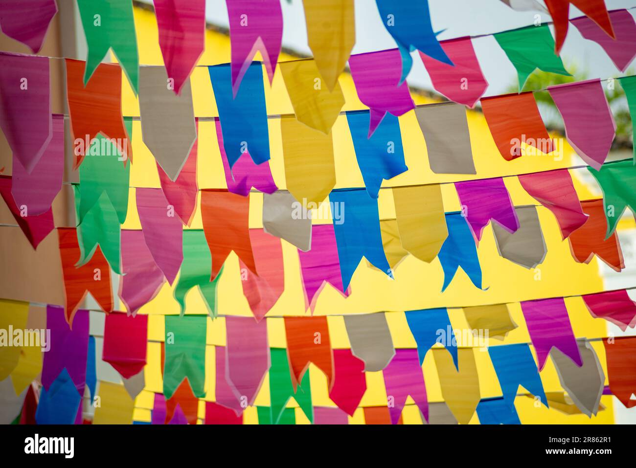 Bandiere di colori diversi appese ad una corda. Decorazione di Sao Joao. Festa di giugno. Contro il muro giallo. Foto Stock