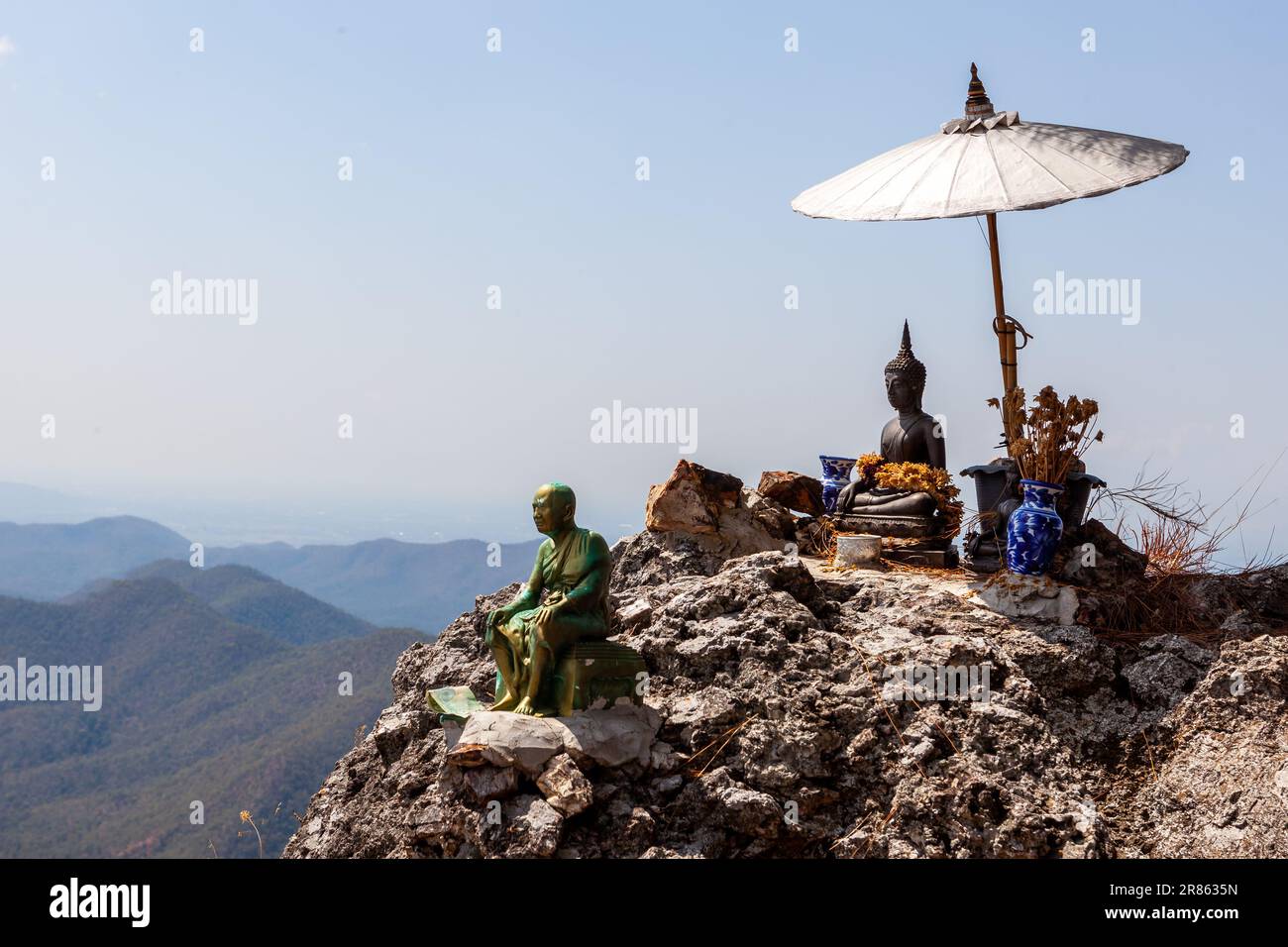 Piccola statua di Buddha sotto un ombrello e splendida vista sul pendio del monte Doi Nangmo vicino a Chiang mai, nel nord della Thailandia. Foto Stock