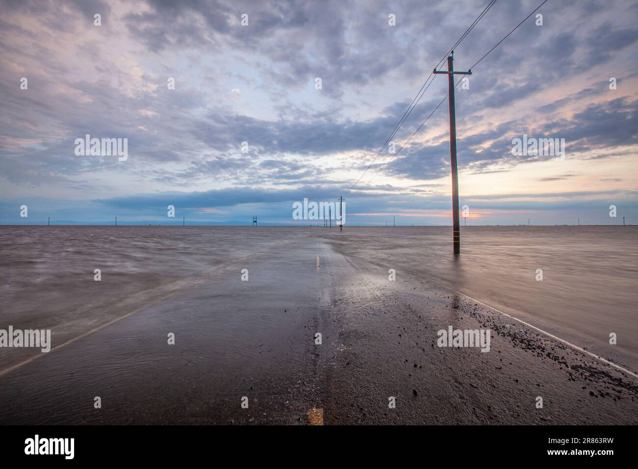 La strada è allagata. Il lago Tulare, situato nella Central Valley della California, è stato per decenni un lago asciutto, ma è tornato alla vita dopo le piogge maggiori d Foto Stock