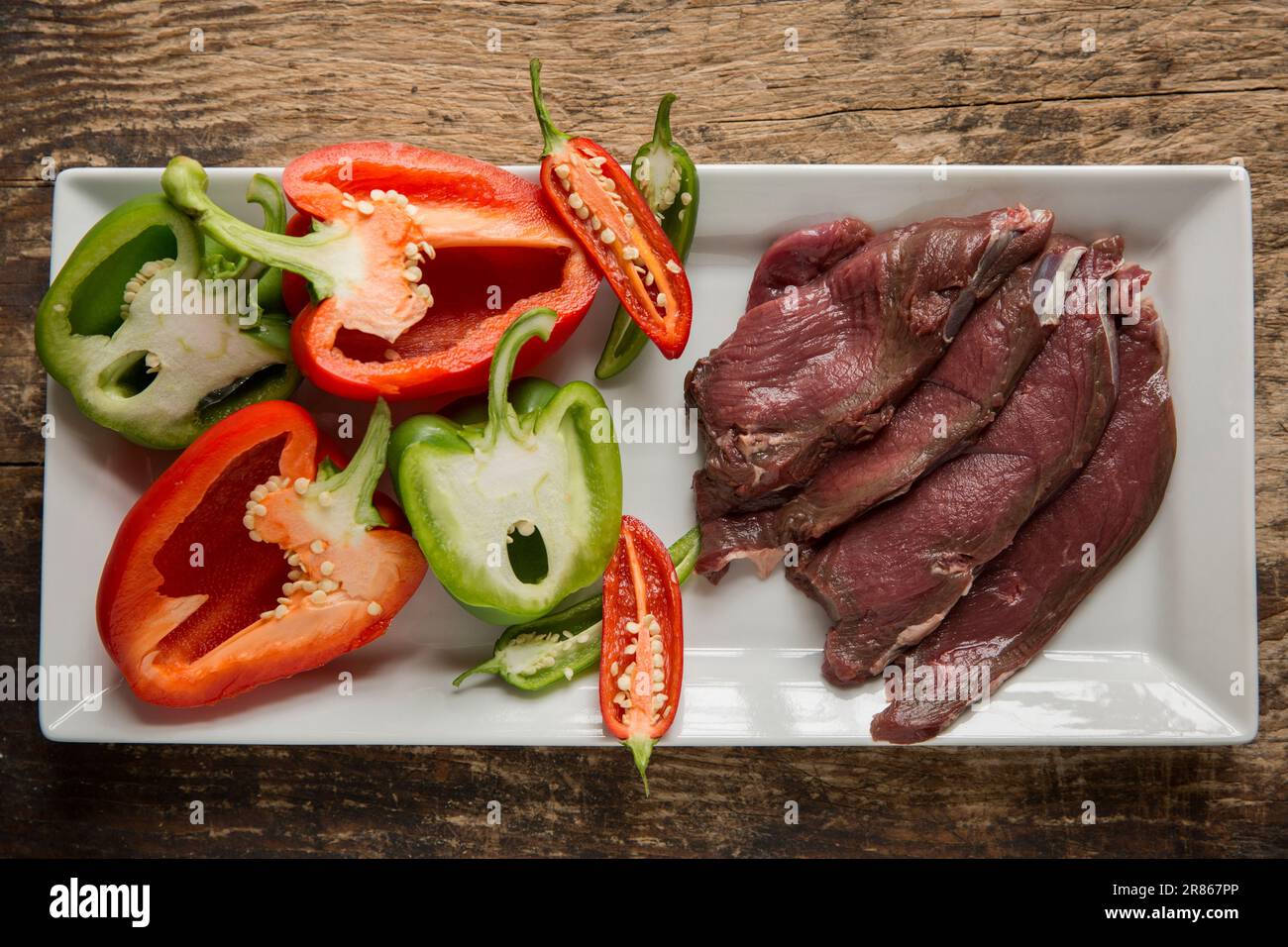 Fette di cervo crudo di capriolo selvatico, Capreolus capreolus, che vengono preparati per essere casalinghi in una salsa di fagioli neri. Inghilterra Regno Unito GB Foto Stock