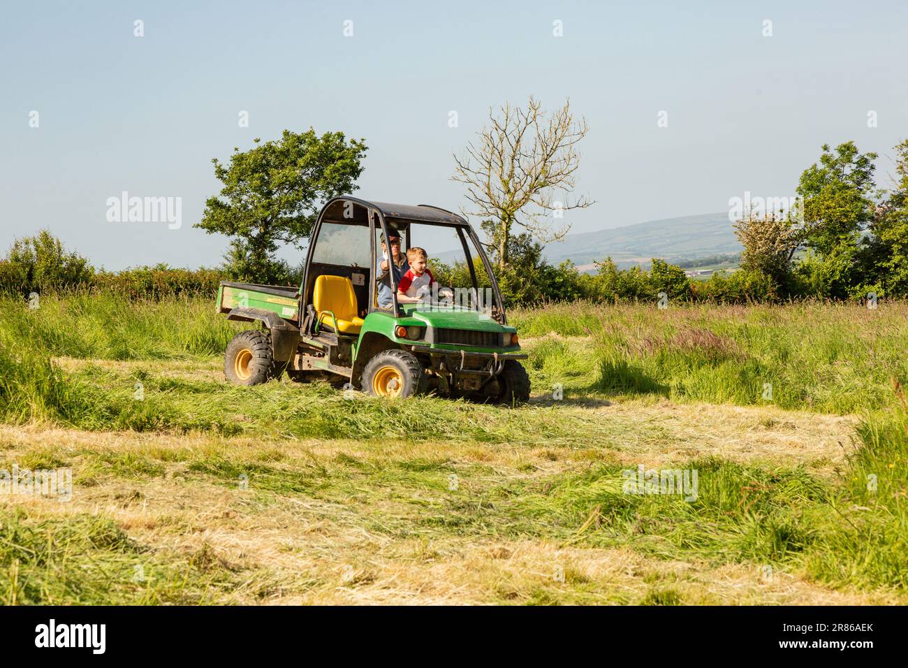 Bambino di sei anni che impara a fare immersioni a un John Deere Gator, High Bickington, North Devon, Inghilterra, Regno Unito. Foto Stock