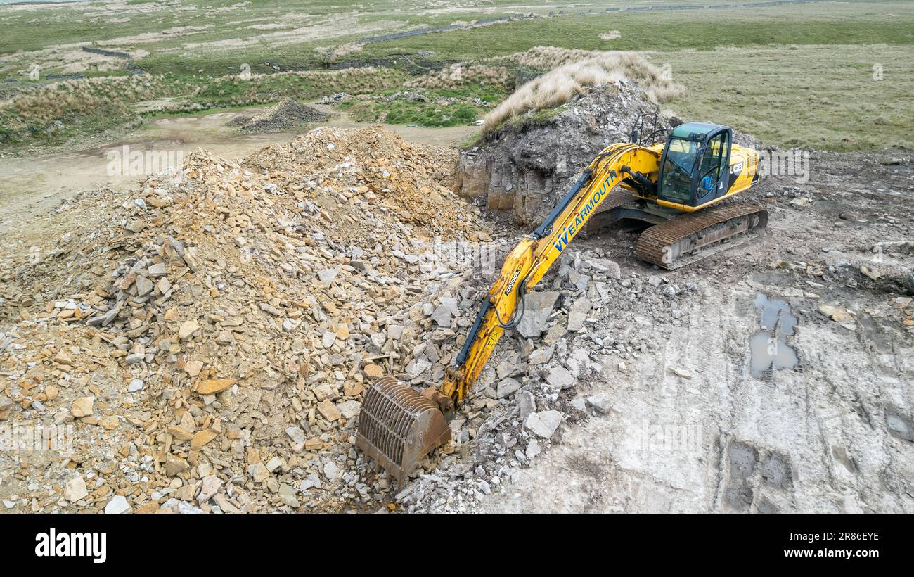 360 escavatore in cava per pietra da utilizzare in muratura a secco nelle aziende agricole locali. Cumbria, Regno Unito. Foto Stock