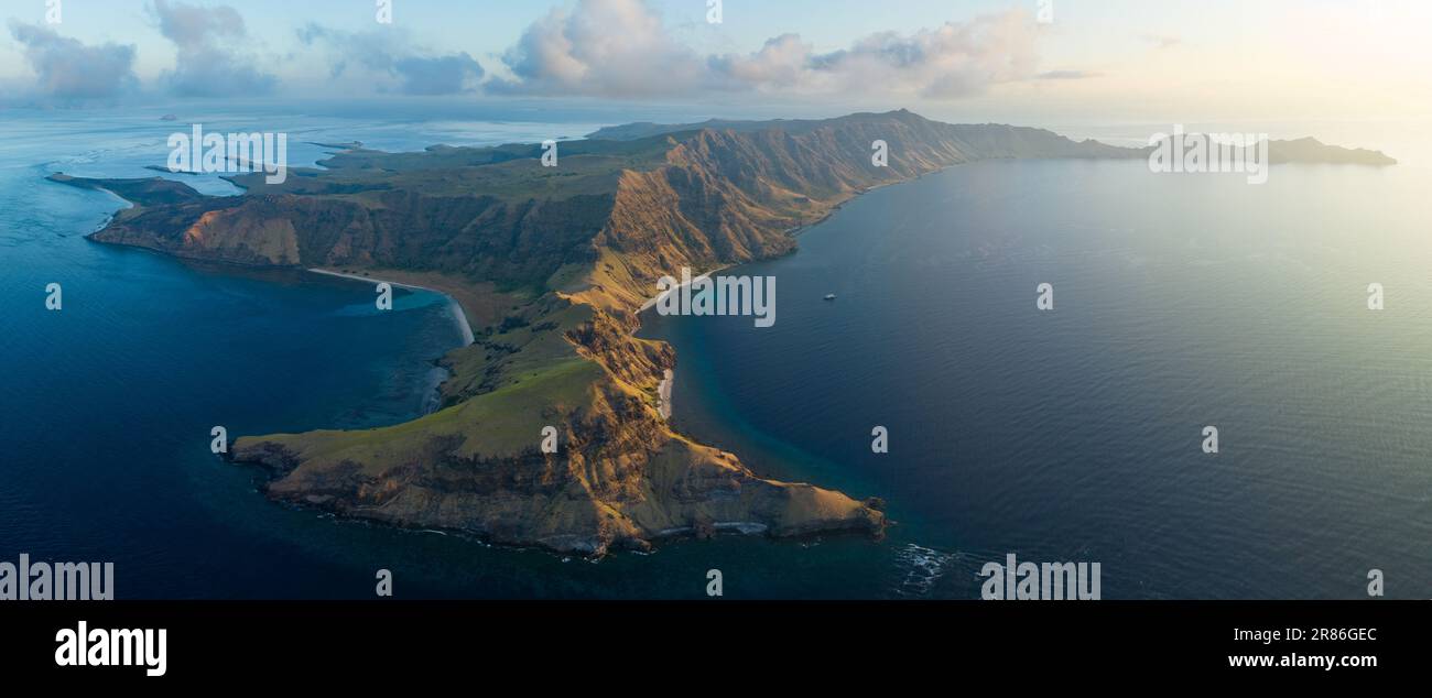 La luce del sole serale illumina l'isola vulcanica di Gili Banta vicino a Komodo, Indonesia. Questa zona tropicale ospita una straordinaria biodiversità marina. Foto Stock