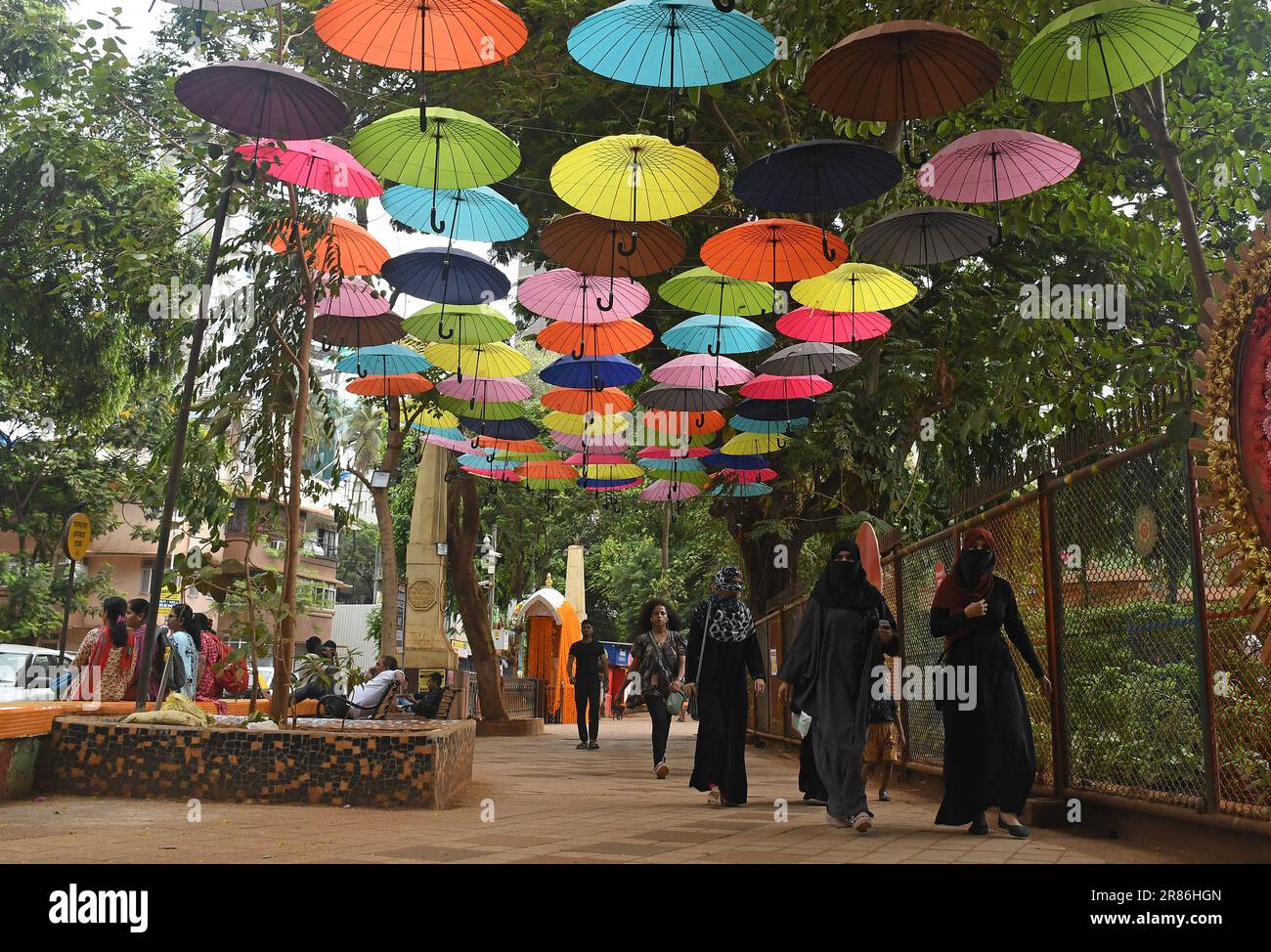 Mumbai, India. 19th giugno, 2023. Si vedono persone che camminano sotto colorati ombrelli installati in un vicolo fuori da un parco giochi a Mumbai. Gli ombrelli sono impiccati come parte del piano di abbellimento prima della stagione monsonica. (Foto di Ashish Vaishnav/SOPA Images/Sipa USA) Credit: Sipa USA/Alamy Live News Foto Stock