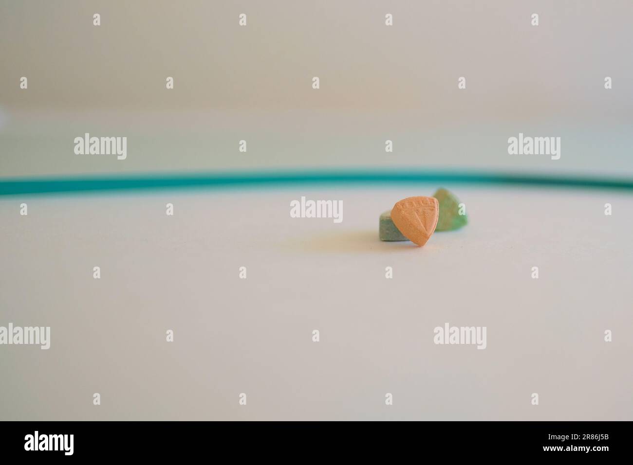Pillole di ecstasy Tesla di colore arancione, verde e blu a forma di scudo con il logo Tesla; 240 milligrammi di farmaci ricreativi MDMA o Molly Foto Stock