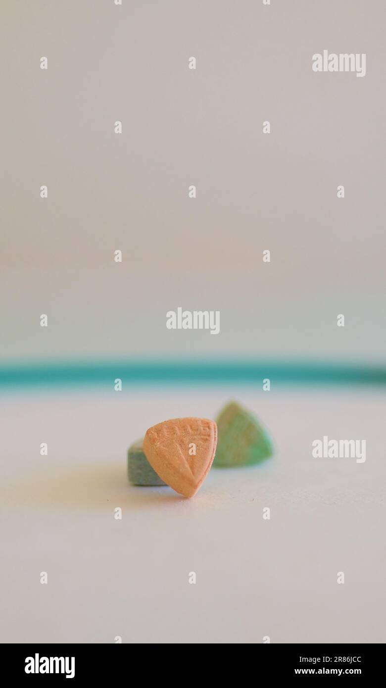 Pillole di ecstasy Tesla di colore arancione, verde e blu a forma di scudo con il logo Tesla; 240 milligrammi di farmaci ricreativi MDMA o Molly Foto Stock