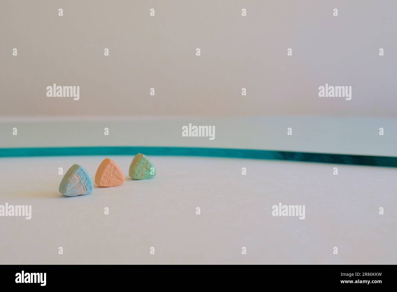 Pillole di ecstasy Tesla di colore arancione, verde e blu a forma di scudo con il logo Tesla; 240 milligrammi di farmaci ricreativi MDMA o Molly Foto Stock