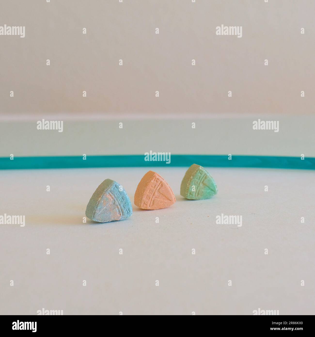 Pillole di ecstasy Tesla di colore arancione, verde e blu a forma di scudo con il logo Tesla; 240 milligrammi di farmaci ricreativi MDMA o Molly Foto Stock