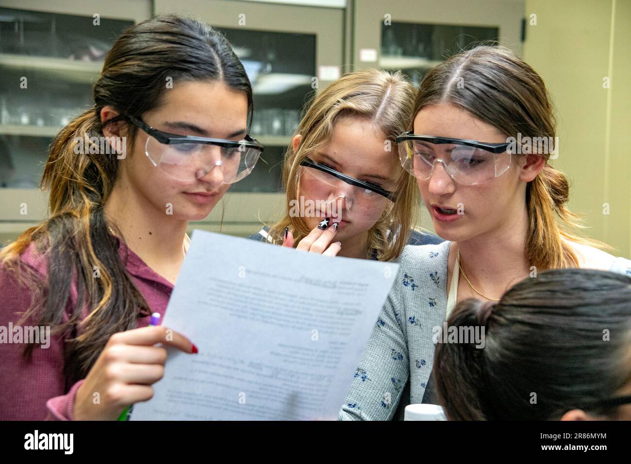 Tre studenti di chimica di San Clemente, CA, High School Advanced Placement (AP) leggono un rapporto del loro ultimo esperimento. Prendere nota degli occhiali di sicurezza. Foto Stock