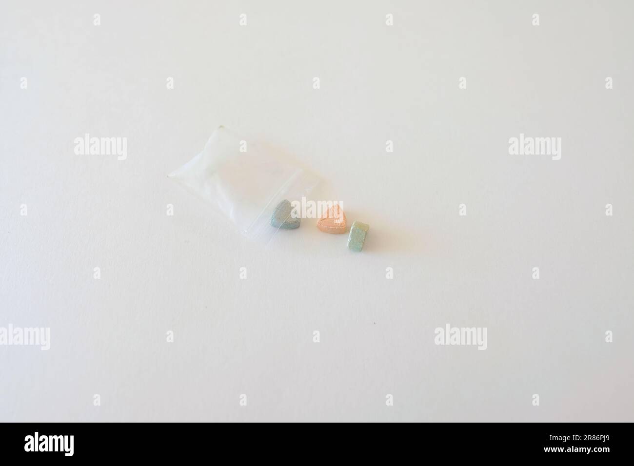 Pillole di ecstasy Tesla di colore arancione, verde e blu a forma di scudo con il logo Tesla; 240 milligrammi di farmaci ricreativi MDMA o Molly Foto Stock