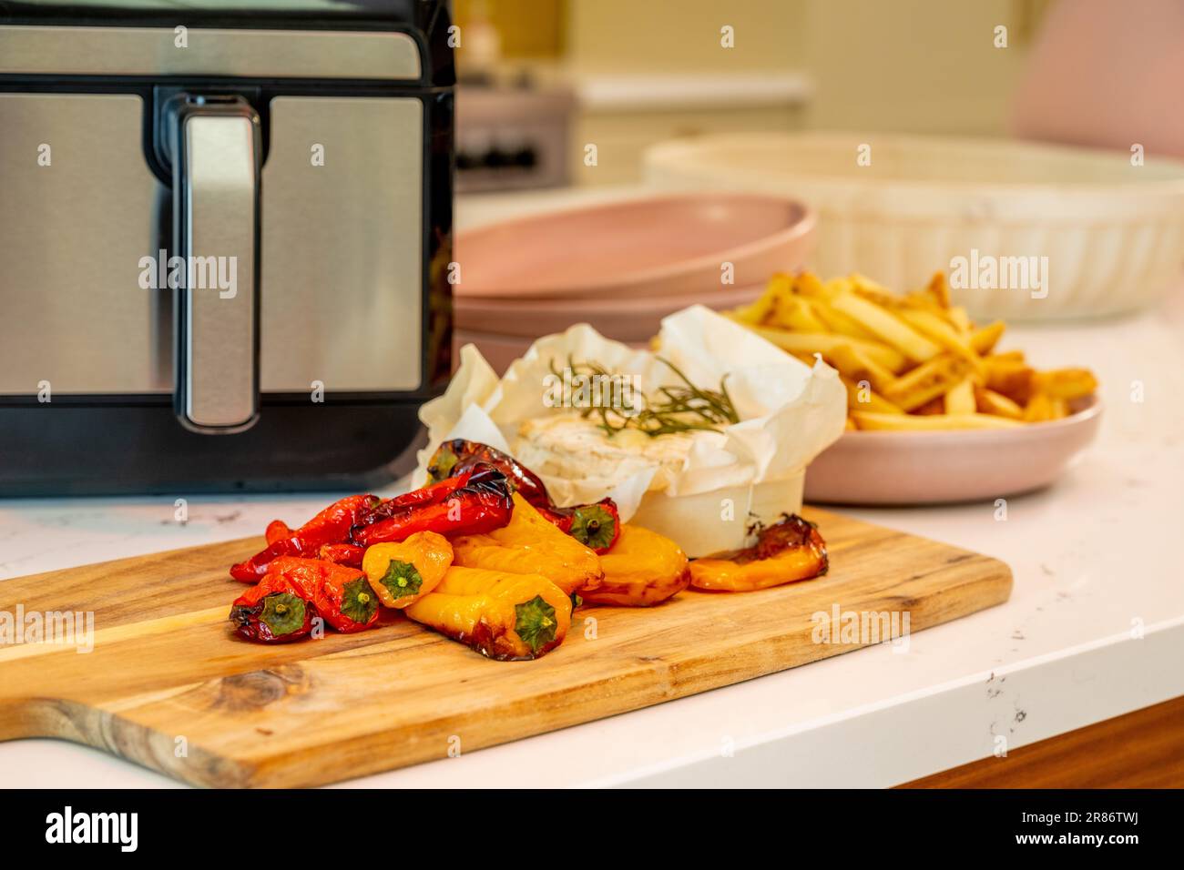 Peperoni arrostiti, camembert al forno e patatine cotte in una friggitrice ad aria, in una cucina domestica. REGNO UNITO Foto Stock