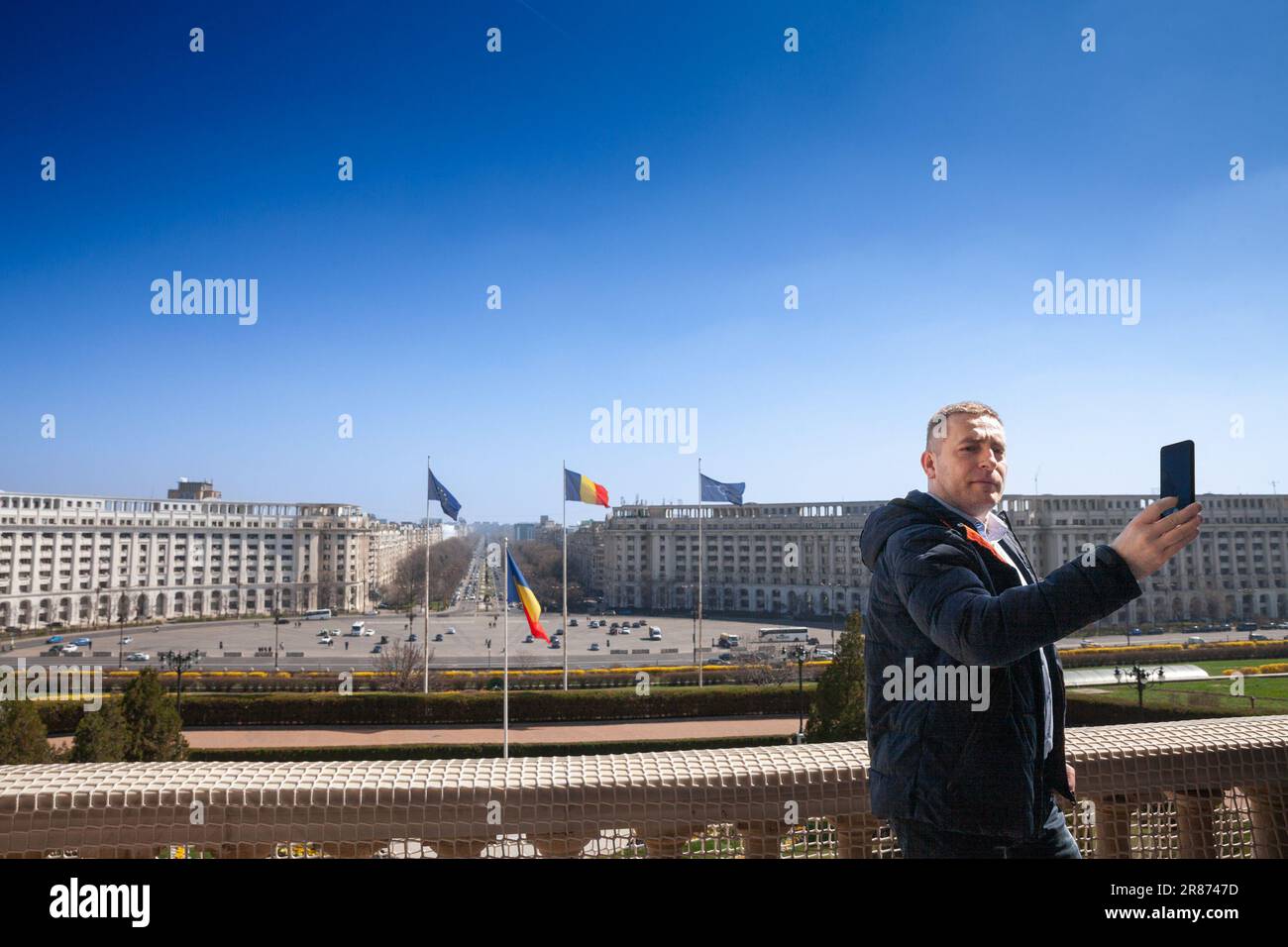 Foto di un turista che scatta una foto selfie con il suo smartphone di fronte a Piazza della Costituzione, o Piata constitutiei dal palazzo rumeno di Parl Foto Stock