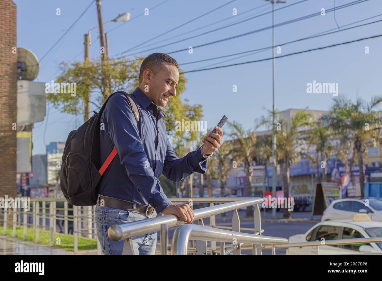 Giovane latino che guarda il suo cellulare con spazio copia.. Foto Stock