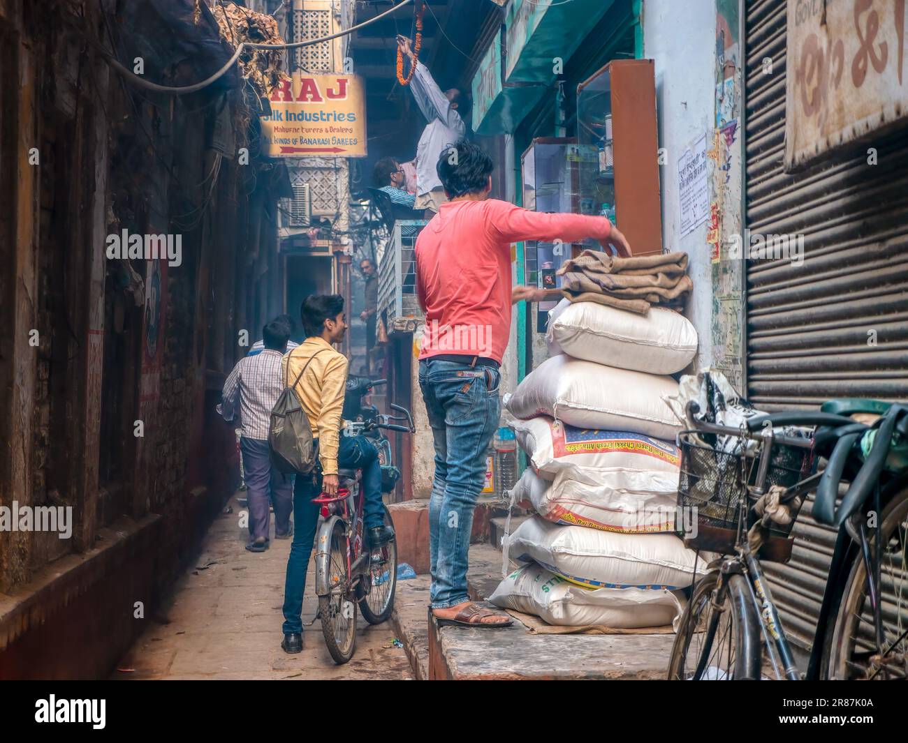 Varanasi, India - 11 novembre 2015. Mercanti locali impegnati a prepararsi ad aprire i loro negozi per la giornata in uno stretto vicolo della città. Foto Stock