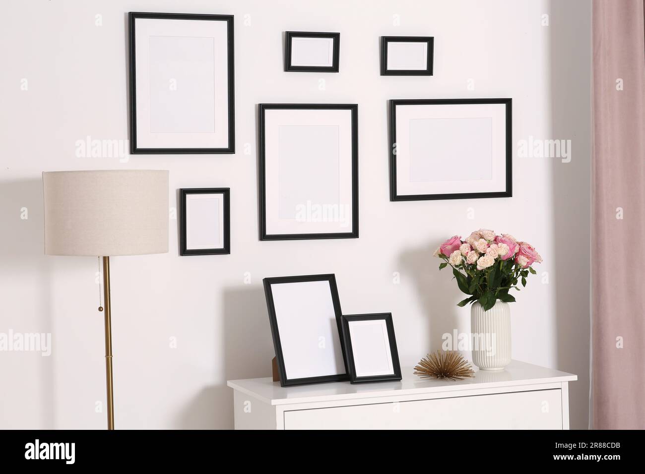 Cornici vuote appese su parete bianca e cassettiera con fiori interni Foto  stock - Alamy