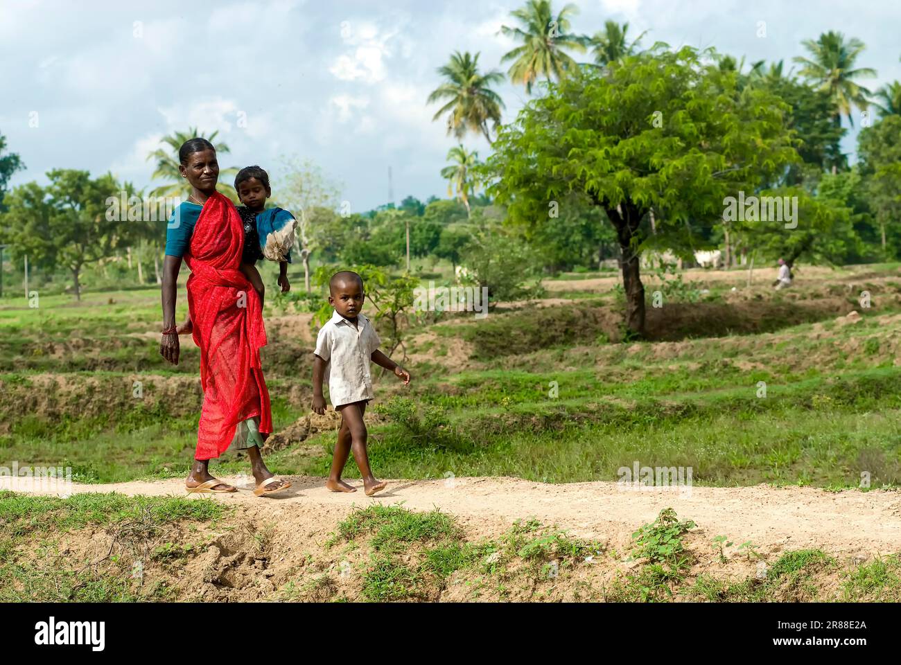 Una donna del villaggio che cammina con la figlia sull'anca e sul figlio, Tamil Nadu, India del Sud, India, Asia Foto Stock