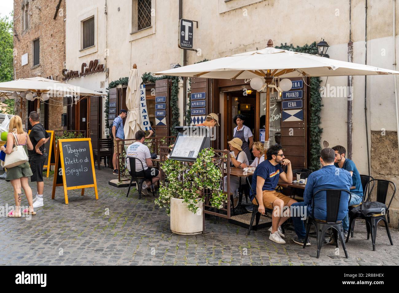 Sidewalk caffè ristorante in una strada acciottolata del quartiere di Trastevere, Roma, Lazio, Italia Foto Stock