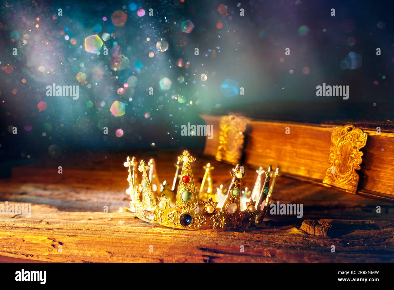 Medievale King Crown and Old Book - storia del regno Fantasy con luci magiche scintillanti e astratte defocalizzate Foto Stock